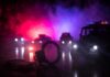 Contempt Charge Explodes in Uniform Handcuffs on a surface with police cars and flashing lights in the background