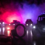 Contempt Charge Explodes in Uniform Handcuffs on a surface with police cars and flashing lights in the background