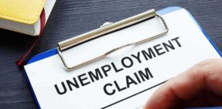 Unemployment claim form on clipboard with hand holding pen