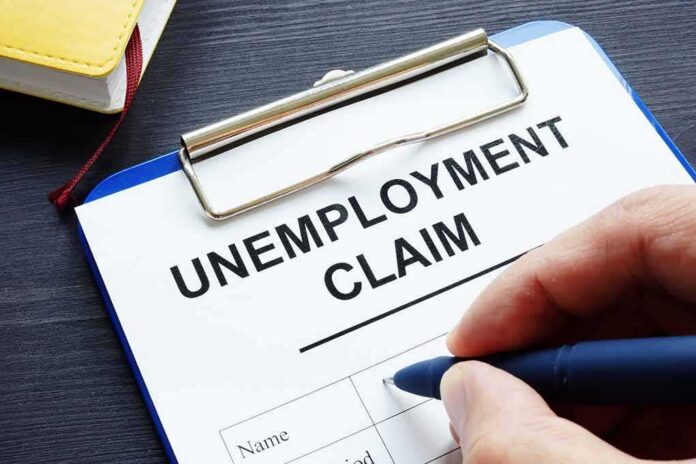Unemployment claim form on clipboard with hand holding pen