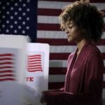 Socialist Surge Rattles Democrats Voter at a polling booth with an American flag backdrop