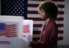 Voter at a polling booth with an American flag backdrop