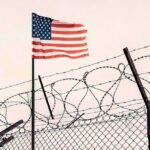 Counter-Terror Raid Shocks Military Base American flag above barbed wire fence