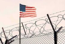 Counter-Terror Raid Shocks Military Base American flag above barbed wire fence