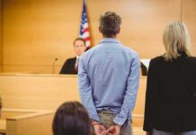 Defendant in handcuffs standing before a judge in a courtroom