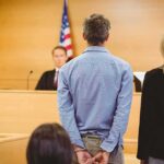 Cape Cod Mansion Shock: Teen, Booze, Charges Defendant in handcuffs standing before a judge in a courtroom