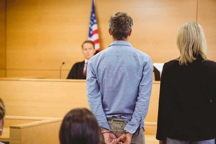 shutterstock_243763714 Defendant in handcuffs standing before a judge in a courtroom