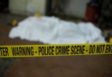 crime scene tape in foreground with covered body in background