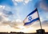 Secret War Huddle Stuns Israel Israeli flag waving against a sunset backdrop with clouds