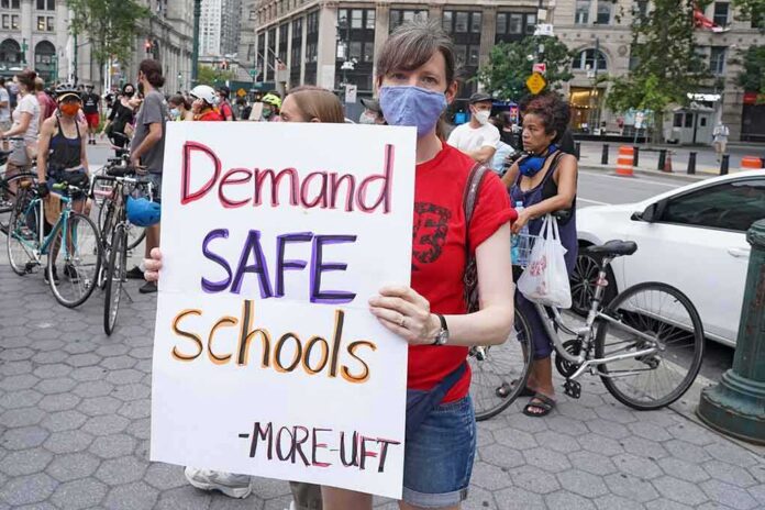 shutterstock_1789804259 Person wearing mask holds protest sign reading Demand SAFE Schools
