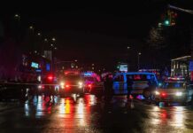 School Riots Turn Brutal Overnight Nighttime police scene with flashing lights on a wet city street