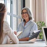 Eligibility Void Ignites League-Wide Firestorm Smiling woman with gray hair talking in a modern office