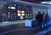 cybersecurity operations room with large data dashboards and people discussing