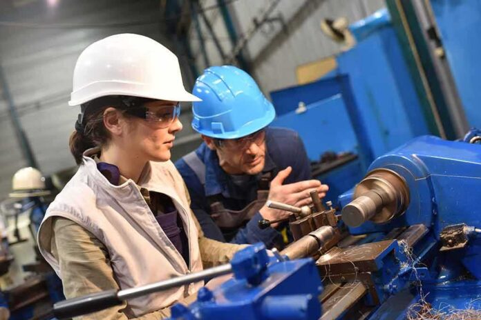 Two workers operating a metal lathe in a workshop