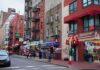 Pete Davidson Torches ‘Fake Staten Island’ City street with brick buildings, fire escapes, and busy storefronts