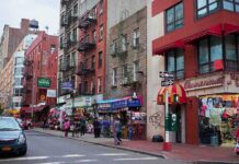 Pete Davidson Torches ‘Fake Staten Island’ City street with brick buildings, fire escapes, and busy storefronts